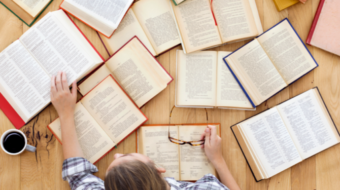 Aerial view of student looking at various open textbooks